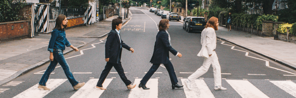 The Bootleg Beatles pictures walking across a zebra crossing on an empty street.